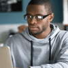 A man looking into the laptop wearing spectacles