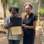 Two people holding a certificate of appreciation.