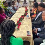 Group of people sitting at a table with flowers.