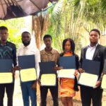 Group of people holding certificates outdoors.